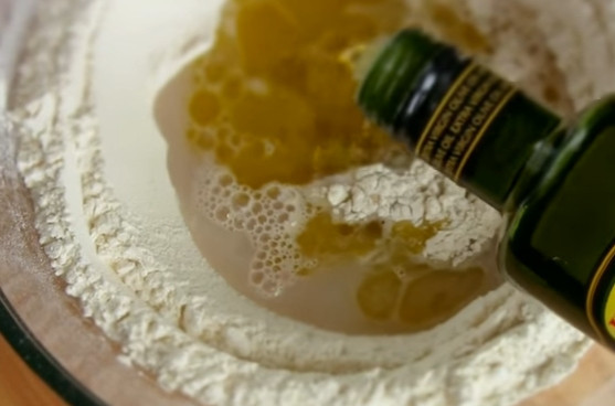 1. Этап. Фокачча с сыром: 3. Сделайте лунку в муке, отправьте туда дрожжевую смесь и остаток воды. Добавьте оливковое масло и вымешивайте тесто 8-10 минут.