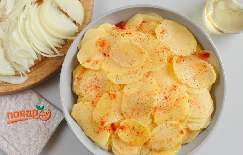 1. Этап. Пирог с картошкой: Подготовьте начинку. Очистите лук и порежьте тонкими полукольцами. Картофель очистите от кожуры, нарежьте тонкими слайсами с помощью специального ножа. Картофель посолите, поперчите, добавьте гранулированный чеснок, копченую паприку, растительное масло и хорошо перемешайте.