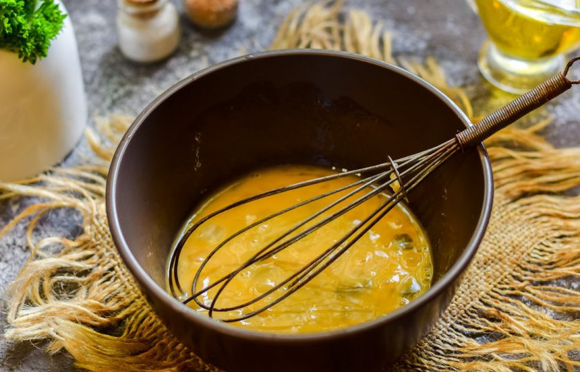 1. Этап. Теплый салат с печенью и омлетом: Вбейте яйцо в глубокую миску, добавьте щепотку соли и взболтайте венчиком.