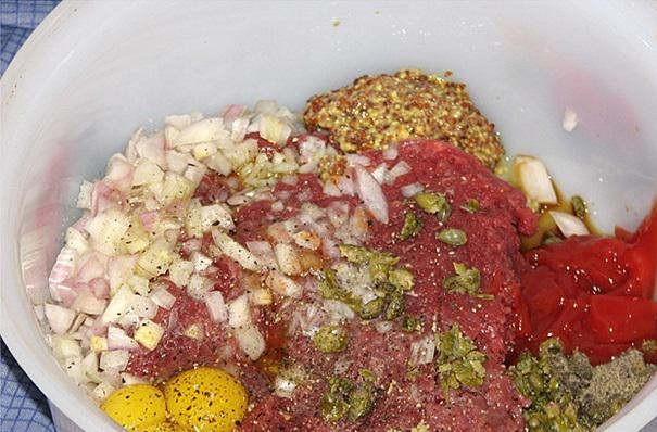 1. Этап. Бифштекс тартар: Конину перемолите в фарш через мясорубку. Добавьте к нему соль, перец, горчицу, томатную пасту и измельчённые каперсы с луком. Также добавьте 4 яйца, уксус и растительное масло.