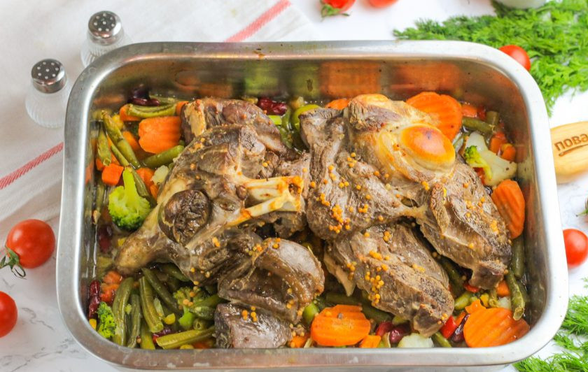 1. Этап. Баранья нога в духовке с овощами: Если используете замороженные смеси, то слегка разморозьте их и сбрызните растительным маслом, посолите и перемешайте. Выложите в форму. Раскройте баранину и переместите ногу на овощи. Запеките все вместе в духовке еще 30 минут, полив баранину оставшимся маринадом.