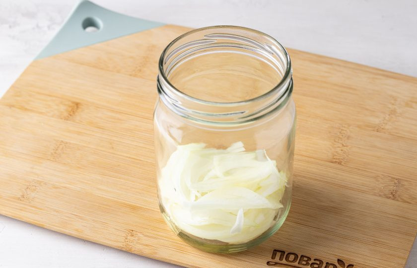 1. Этап. Салат на зиму с огурцами и помидорами: На дно чистой банки добавьте растительное масло. Нарежьте репчатый лук перьями и выложите на дно банки.