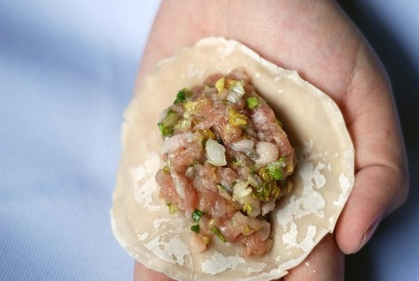 1. Этап. Китайские пельмени: 4. Муку просейте в миску, смешайте с водой и замесите тесто. Тесто сверните в колбаску и порежьте на одинаковые кусочки. Каждый кусочек обваляйте в муке, затем сделайте из него шарик. Каждый шарик тонко раскатайте. На центр полученной лепешечки выложите чайную (или больше) ложку начинки.