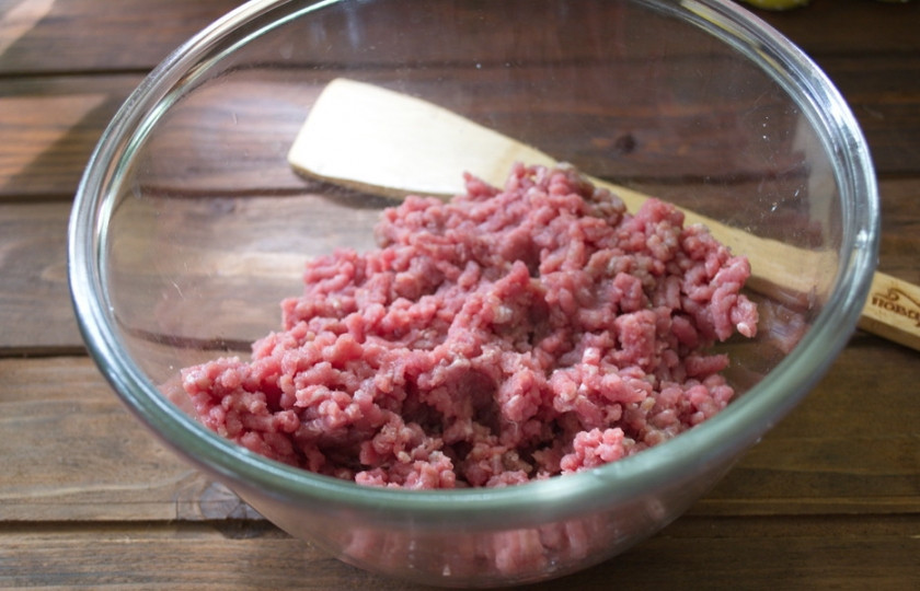 1. Этап. Мясной рулет с грибным соусом: Говяжий фарш выкладываем в миску. Добавляем соль, перец, специи по вашему выбору. Вливаем 1 стакан воды и вымешиваем.