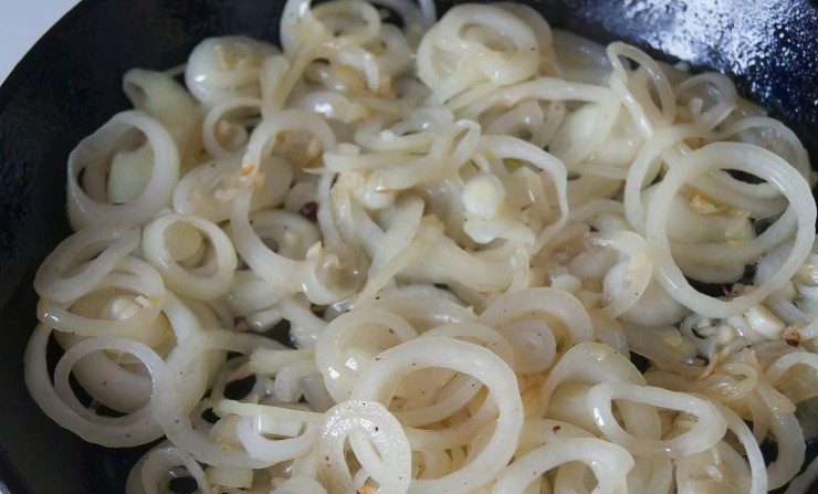 1. Этап. Мясо по-фламандски: Перекладываем обжаренный бекон на тарелку, а вытопленный жир переливаем в утятницу или кастрюлю с толстыми стенками. В сковороде оставляем только пару ложек жира. Репчатый лук нарезаем кольцами, а чеснок измельчаем, обжариваем их на сковороде с оставшимся жиров до мягкости.