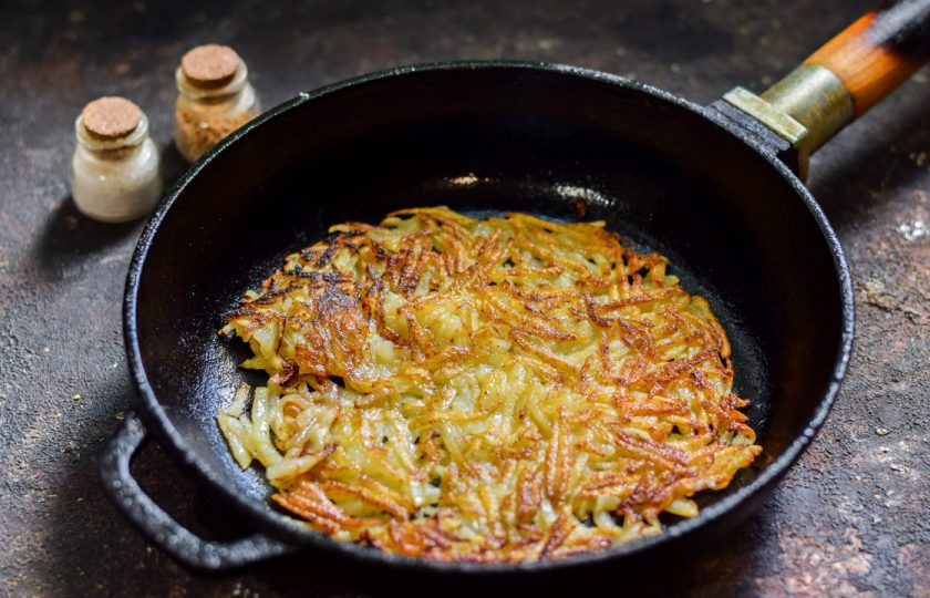 1. Этап. Хашбраун с беконом и сыром: Картофель разложите в той же сковороде тонкой лепешкой. Поджарьте с одной стороны до румяности — 3 минуты, переверните.