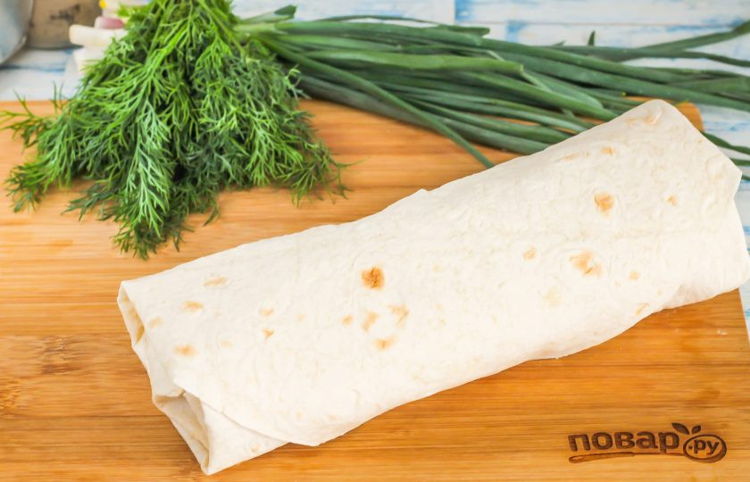 1. Этап. Денеры в лаваше: Полейте всю начинку соусом и сверните лаваш рулетом, стараясь не сильно сжимать начинку, чтобы лаваш не лопнул.