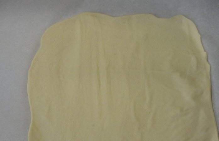 1. Этап. Ушки из теста: На присыпанном мукой столе раскатайте слоеное тесто в тонкий пласт.