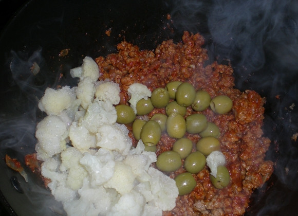 1. Этап. Цветная капуста, тушеная с фаршем: Теперь в глубокую сковороду или в казан наливаем оливковое масло и жарим на нем лук и чеснок до золотистого цвета. Выкладываем фарш, солим и перчим, тушим в течение 5 минут на среднем огне. Затем добавляем томатную пасту, перемешиваем и еще 10 минут тушим все. Теперь очередь цветной капусты и оливок. Выкладываем их в сковороду, заливаем все горячей водой и готовим под закрытой крышкой на медленном огне примерно 25 минут. Получается очень вкусное и довольно красивое блюдо. Приятного всем аппетита!