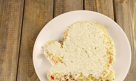 1. Этап. Салат Варежка Деда Мороза: 5. Следующим слоем будут отваренные вкрутую яйца, натертые на терке. Добавьте к ним щепотку соли и немного майонеза, перемешайте и выложите аккуратно поверх сыра.