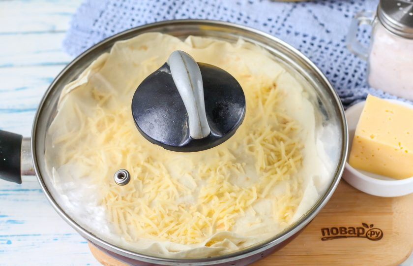 1. Этап. Пирог из лаваша на сковороде: Накройте сковороду крышкой и поместите на плиту, включая минимальный нагрев. Томите пирог до расплавления сыра и до характерного вкусного аромата поджаренной выпечки. Примерно 6-10 минут.