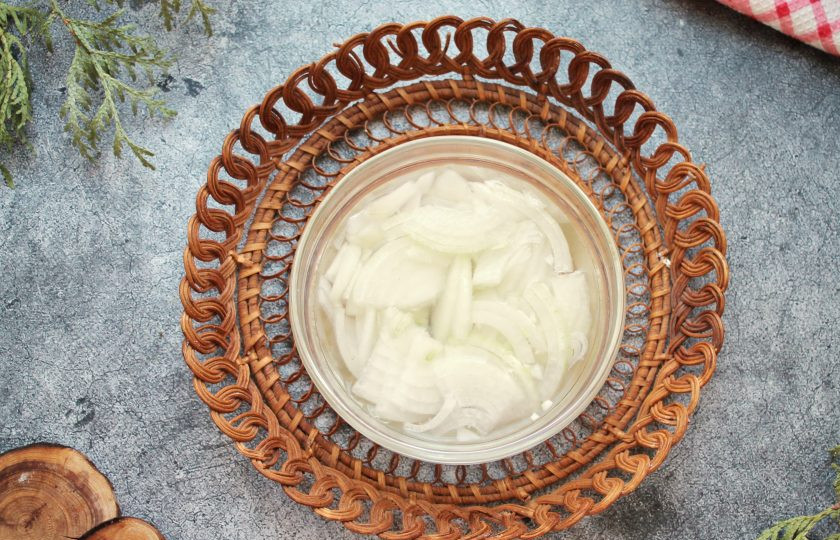 1. Этап. Мясо по-французски со свининой: Репчатый лук почистите и порежьте четвертинками, выложите в миску. Влейте воду, уксус и оставьте на 15 минут. Откиньте лук на сито и дайте маринаду полностью стечь.