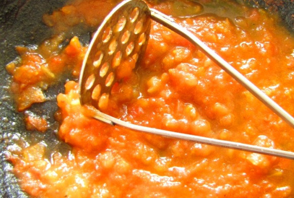 1. Этап. Соус для хинкали: Выкладываем нарезанный помидор на сковороду и тушим его, пока он не станет мягким, разминаем массу толкушкой.