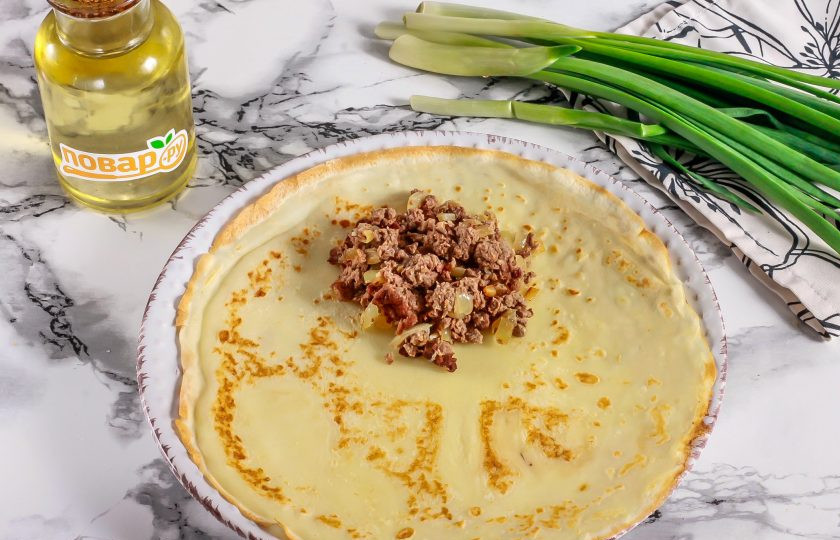 1. Этап. Блинчики со свиным сердцем: Испеките таким образом и остальные блины. На край каждого блина выложите 1,5 ст.л. фарша. Закрутите блин рулетиком, сначала закрывая внутрь края.