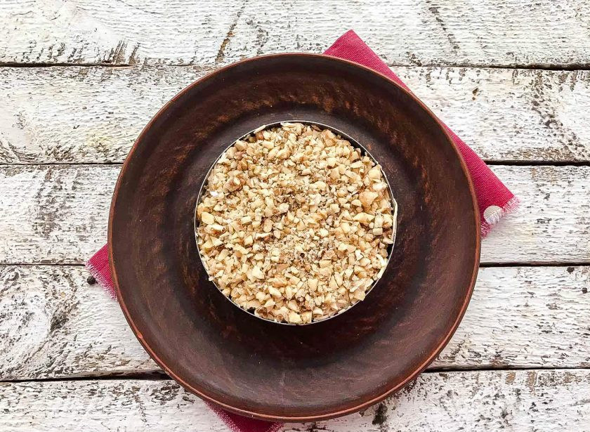 1. Этап. Салат с мандаринами: Грецкий орех очистите от скорлупы, мелко нарежьте ножом и посыпьте им салат.