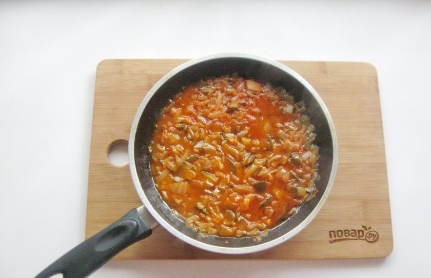 1. Этап. Солянка с солеными грибами: Налейте рафинированное подсолнечное масло и 100 миллилитров куриного бульона. Накройте сковороду крышкой и тушите лук с огурцами и томатной пастой 15-20 минут.