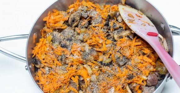 1. Этап. Гречка с грибами и мясом: Соедините мясо и грибы в одной сковороде, посыпьте сверху луком и морковкой и обжарьте 5 минут, пока овощи не подрумянятся и не пустят сок.