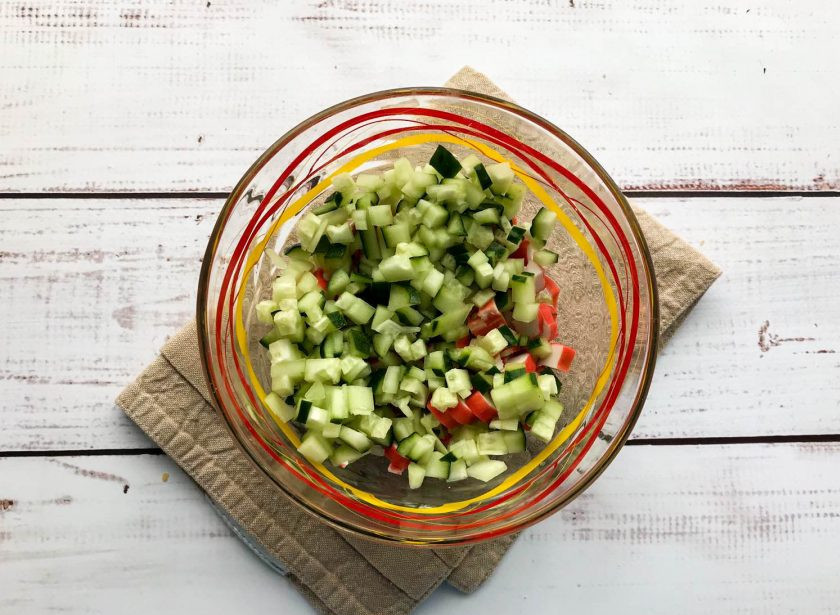 1. Этап. Крабовый салат со сметаной: Огурец помойте под проточной водой, обсушите бумажным полотенцем и нарежьте маленькими кусочками.