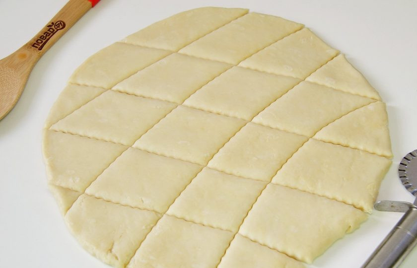 1. Этап. Слоеное печенье на сметане: Затем раскатайте тесто, толщиной примерно 5-7 мм. Чем толще пласт, тем больше печенье будет слоиться. Нарежьте пласт на кусочки. Можно обычным ножом, можно фигурным как у меня, а можно вырезать печенье формочками.