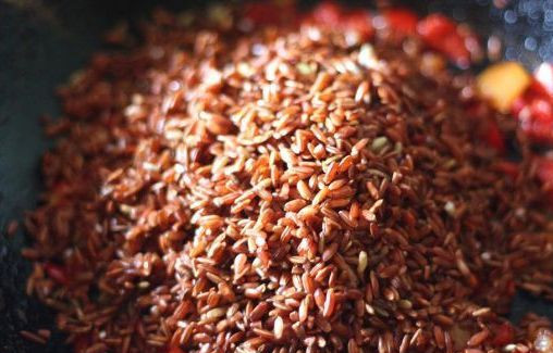 1. Этап. Плов из красного риса: Пока овощи жарятся, мы промываем тщательно рис и выкладываем его на сковороду, перемешиваем все и еще пару минут жарим, помешивая. Потом заливаем рис с овощами водой, добавляем соль и специи по вкусу, доводим жидкость до кипения. Далее мы уменьшаем огонь до минимального, накрываем сковороду крышкой и готовим рис в течение одного часа.