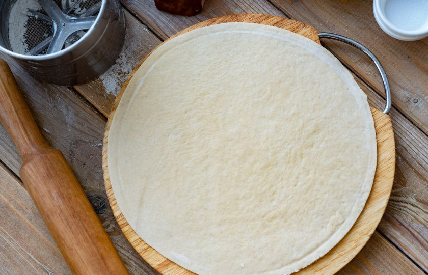 1. Этап. Кальцоне с ветчиной: Затем все тесто поделите на две равные части. Одну часть теста тонко раскатайте с помощью скалки в форме круга (у меня диаметр 26 см).