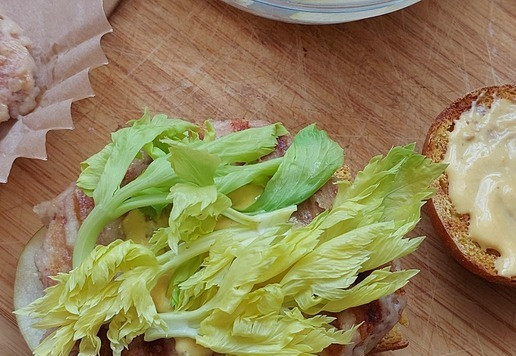 1. Этап. Манговый Верзила с котлетой из индейки: Выкладываем листья сельдерея. Смазываем нижнюю сторону выпуклой булочки