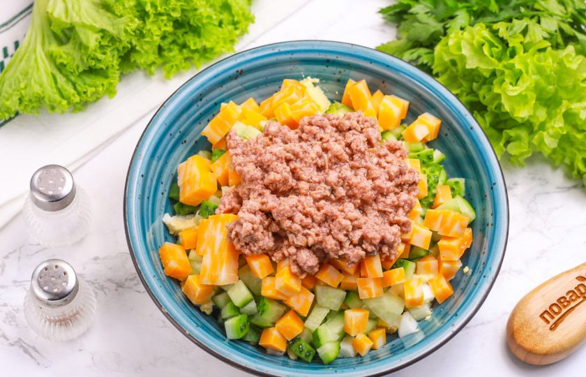 1. Этап. Салат с огурцом, сыром и тунцом: Выложите консервированного тунца (стружку или части). По желанию можно помять кусочки рыбы вилкой.