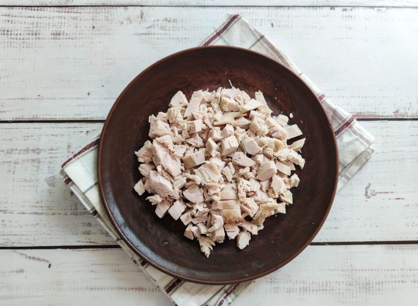 1. Этап. Салат Броненосец: Остывшую курицу нарежьте маленькими кусочками и выложите на дно тарелки.