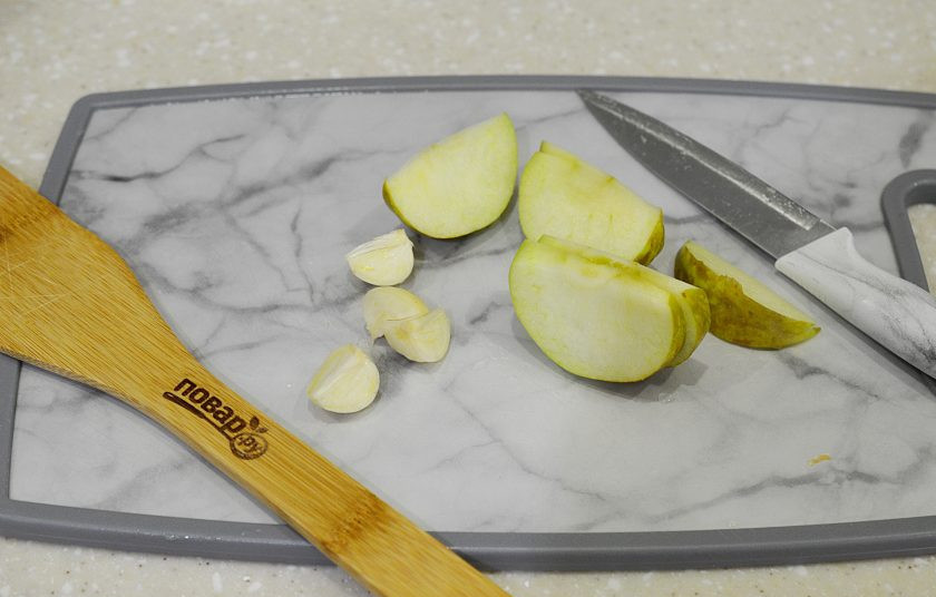 1. Этап. Курица, запеченная в беконе: 5. Яблоко нарежьте дольками, чеснок почистите. Начините курицу.