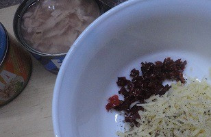 1. Этап. Пикантные канапе с тунцом: Вяленые помидоры в масле мелко нарезать. Сыр натереть на мелкой терку