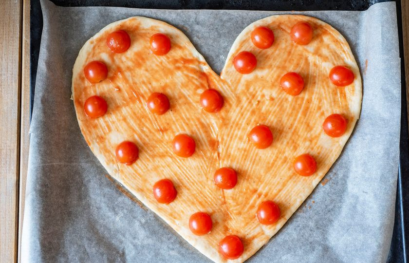 1. Этап. Пицца Сердце: Затем поверхность основы из теста смажьте тонким слоем соуса и разложите равномерно половинки помидорок черри.