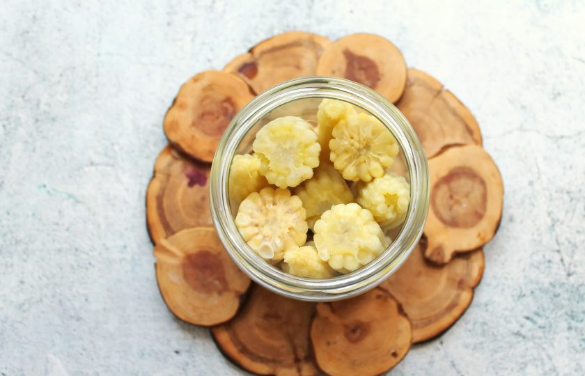 1. Этап. Мини-кукуруза в банке на зиму: В стерилизованные банки выложите перец, гвоздику и плотно выложите кукурузу.