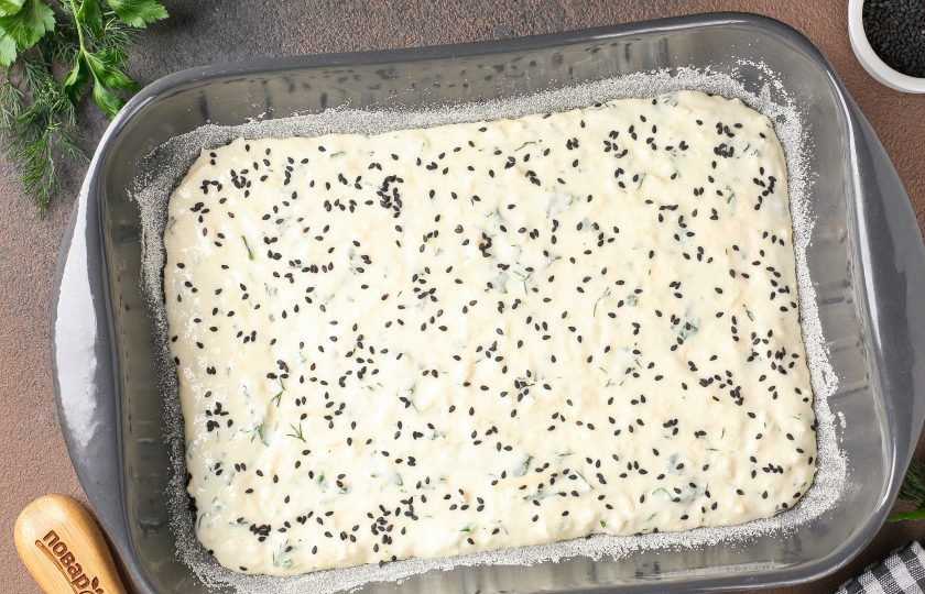 1. Этап. Манник с сыром: Жаропрочную форму смажьте маслом и присыпьте манкой. Выложите тесто и разровняйте лопаткой. Посыпьте тесто кунжутом. Выпекайте в духовке при температуре 180 градусов около 40 минут.