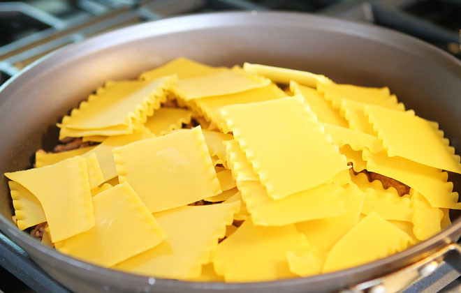 1. Этап. Лазанья на сковороде: Добавьте нарезанные мелко сосиски и поломанные листы лазаньи.