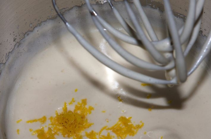 1. Этап. Мадлен: 4. Натрите цедру лимона и добавьте во взбитые яйца, а также через сито всыпьте муку.