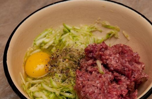 1. Этап. Котлеты из кабачков и фарша: Перекладываем в миску к тертым кабачкам фарш, разбиваем яйцо, солим и перчим. При желании вы можете добавить специи по своему вкусу.