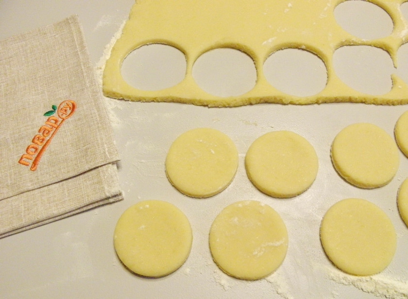 1. Этап. Коржики классические: Притрусите стол мукой. Раскатайте тесто толщиной 5 мм. Стаканом или формой для печенья выдавите коржики, диаметр 8 см. Включите прогреваться духовку на 200 градусов.