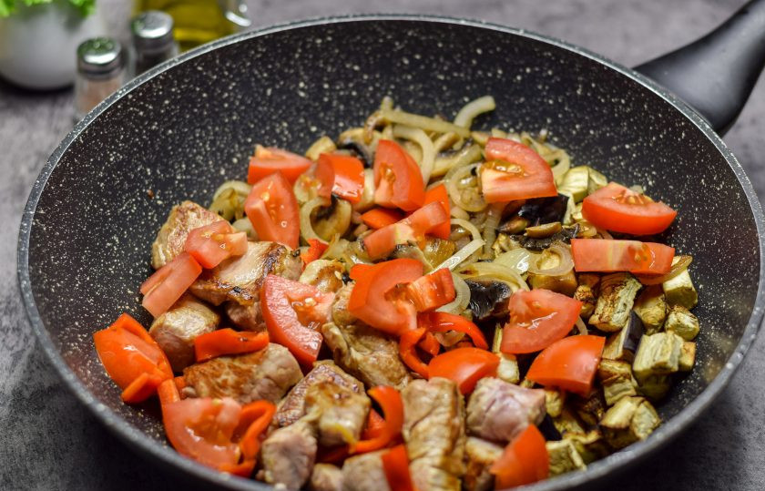 1. Этап. Жаркое из свинины с грибами и баклажанами: Соедините все подготовленные ингредиенты в общей глубокой сковороде, добавьте крупно нарезанные помидоры, специи. Прикройте сковороду крышкой и томите 30-40 минут.