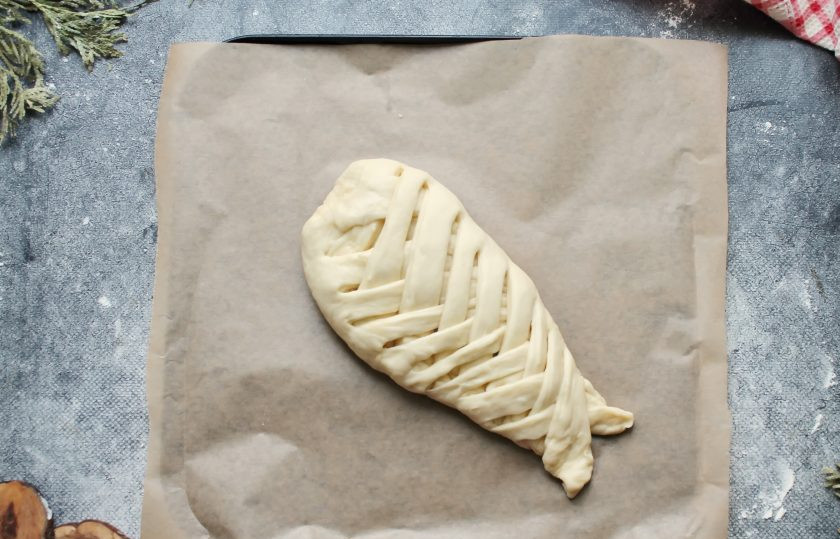 1. Этап. Лещ запеченный в тесте: Начиная со стороны головы, заплетите косичку, закрывая рыбу и формируя пирог. Переложите леща в тесте на противень с пергаментом, накройте и дайте постоять в теплом месте 20 минут.