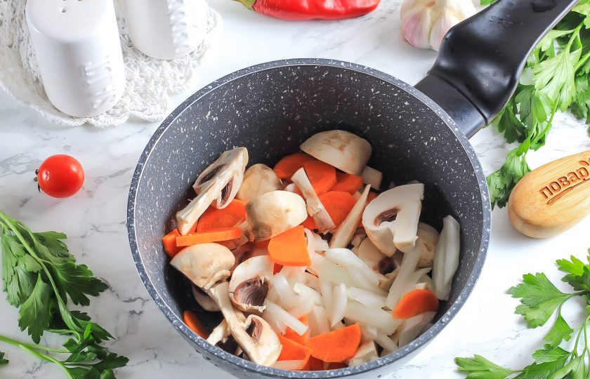 1. Этап. Японский суп с лососем: Промойте грибы и нарежьте их на четвертинки. Лук — лентами, а морковь — брусочками или полукольцами. Выложите все в казан или кастрюлю.