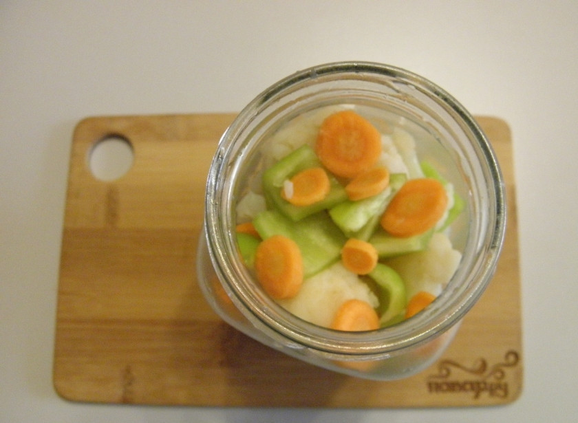 1. Этап. Закатка цветной капусты: В стерильную баночку на дно уложите часть перца и моркови. Заполните треть баночки капустой. Далее — снова перец и морковь, капуста. Вложите по лавровому листочку на баночку и по 1-2 перчинки острой.