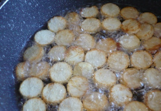 1. Этап. Салат рождественский Золотое полено: В кастрюле на сильном огне разогрейте большое количество растительного масла. Обжарьте нарезанные кружочки картофеля до золотистого цвета.