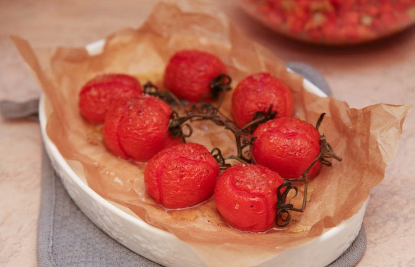 1. Этап. Рыбное филе, жаренное с овощами и креветками: Первым делом необходимо запечь томаты. Для этого вымойте их и выложите на застеленный и смазанный оливковым маслом пергамент, сбрызните маслом сверху, посолите и поперчите. Запекайте при двухстах градусах в духовке около десяти минут.