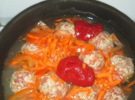 1. Этап. Ежики на сковороде: 4. Теперь из фарша формируем шарики, помещаем их на дно глубокой сковородки. Сверху присыпаем морковью, заливаем водой, добавим томатную пасту и специи по вкусу.