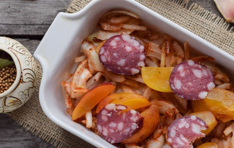 1. Этап. Печень цыплят бройлеров: Возьмите кусочек колбаски и нарежьте его кусочками. Выложите колбаску на лук, она придаст приятный копченый аромат блюду.