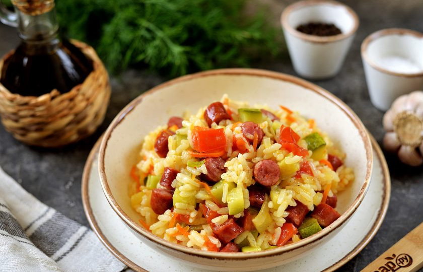 1. Этап. Рис с колбасками и овощами: Спустя время разрыхлите рис вилкой, разложите по порционным тарелкам и подавайте к столу. Очень вкусный рис с колбасками и овощами готов. Приятного аппетита!