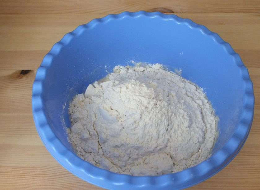 1. Этап. Пельмени с сыром и мясом: Воду с яйцом перелейте в чашу. Добавьте просеянную муку и замесите тесто.