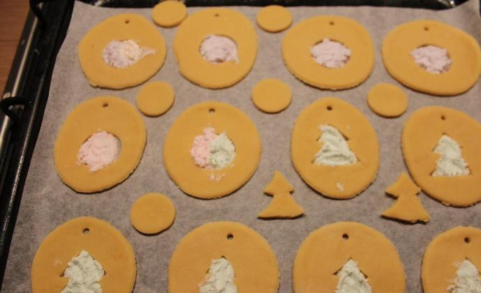 1. Этап. Новогоднее печенье на елку: Разложите печенье на противне, в центральные отверстия насыпьте с горкой порошка из леденцов. Цвета комбинируйте на ваше усмотрение. Поставьте в разогретую до 180 градусов духовку на 5 минут.