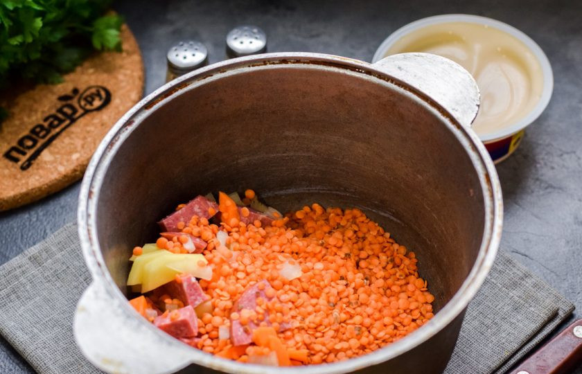 1. Этап. Суп с чечевицей и сыром: Переложите все подготовленные ингредиенты в кастрюлю, добавьте чечевицу. Залейте в кастрюлю горячую воду, доведите до кипения и варите 25 минут.