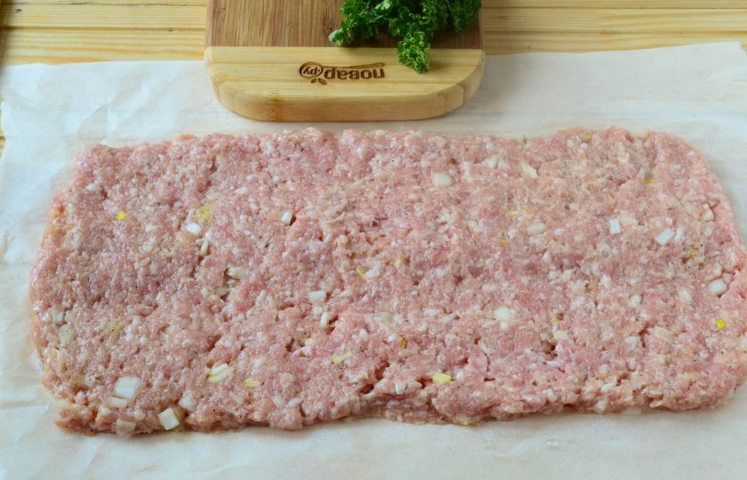 1. Этап. Сытные фрикаделины с начинкой: Выложите фарш на бумагу для запекания в форме прямоугольника.